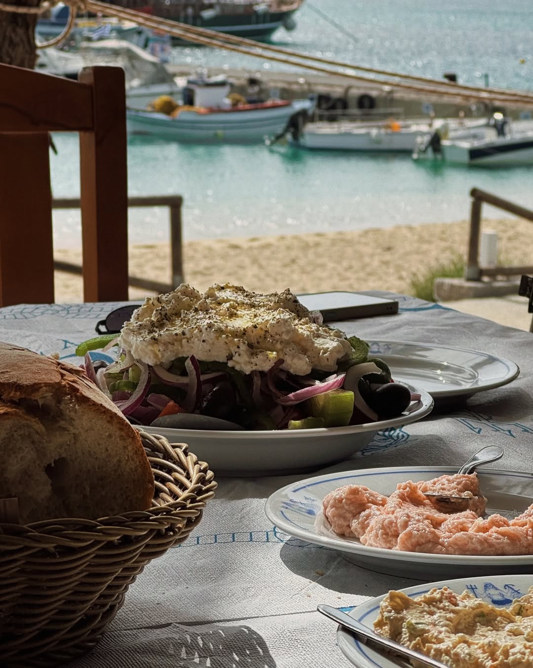 Traditional Greek salad with fresh vegetables, crumbled feta cheese, and olive oil, served with rustic bread at Gorgona Taverna's seaside location with turquoise Aegean Sea backdrop