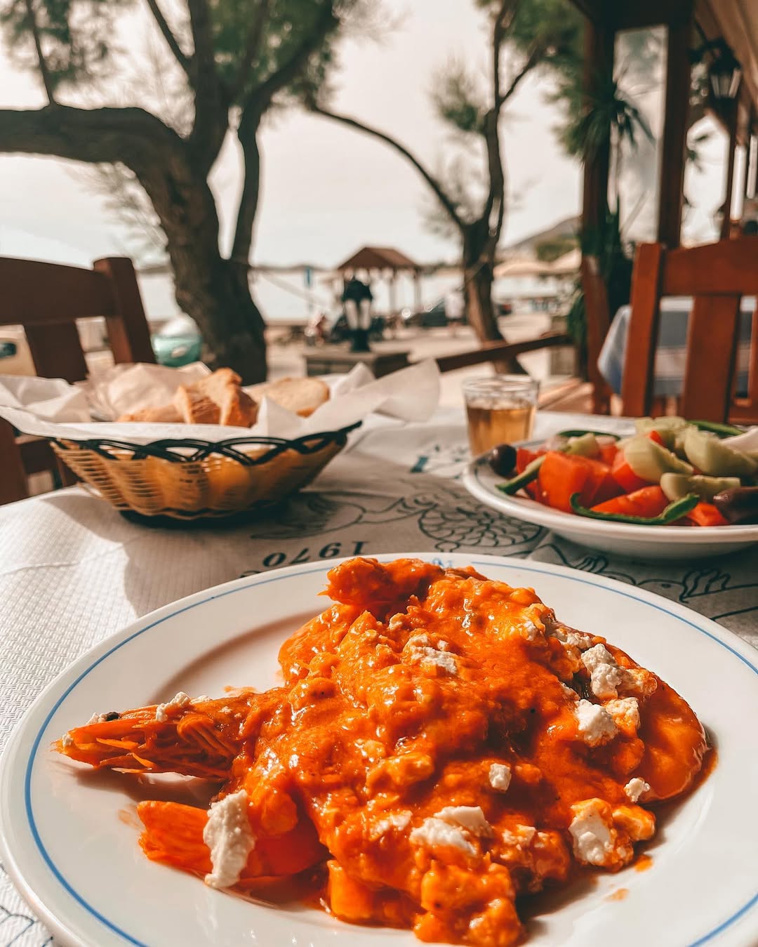 Fresh octopus salad with tender octopus, capers, and herbs, served on white plate at Gorgona Taverna with traditional Greek table setting and olive oil bottles