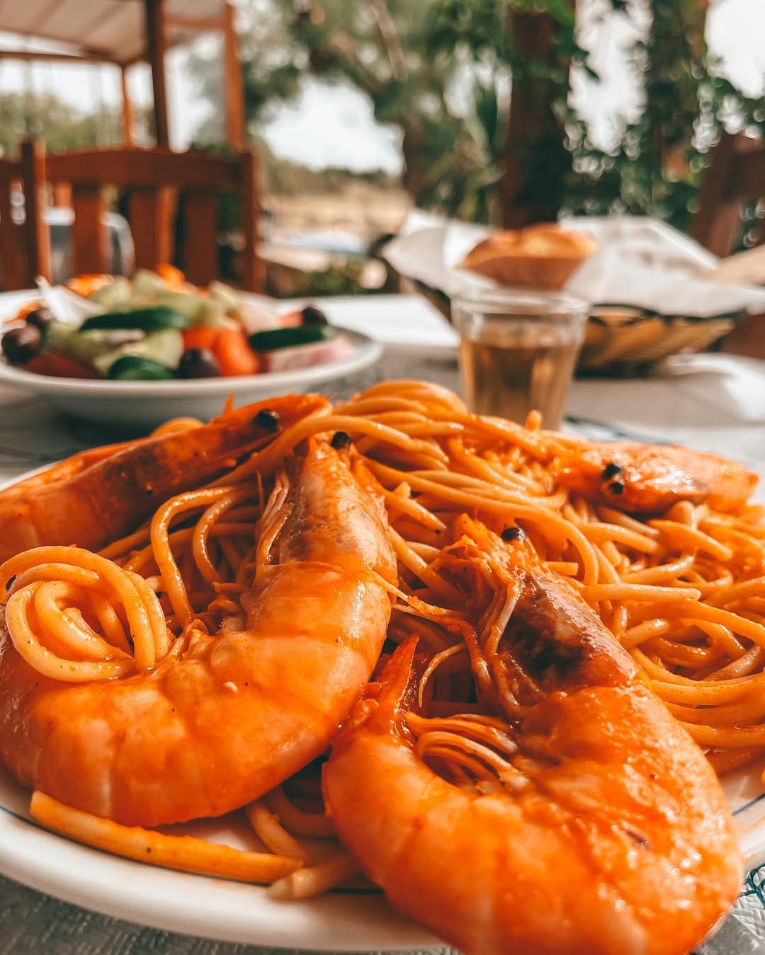 Fresh spaghetti with large, bright orange prawns in tomato sauce, served at Gorgona Taverna's outdoor dining area with Mediterranean ambiance and sea view