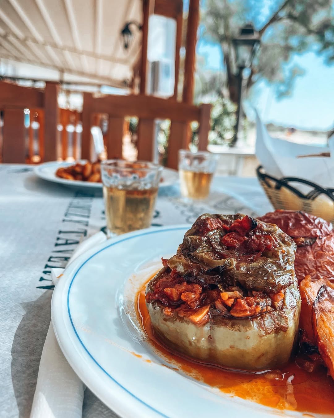 Traditional Greek stuffed vegetables (gemista) with tomatoes and peppers in rich tomato sauce, served on Gorgona Taverna's distinctive blue-patterned tablecloth with 'since 1970' branding
