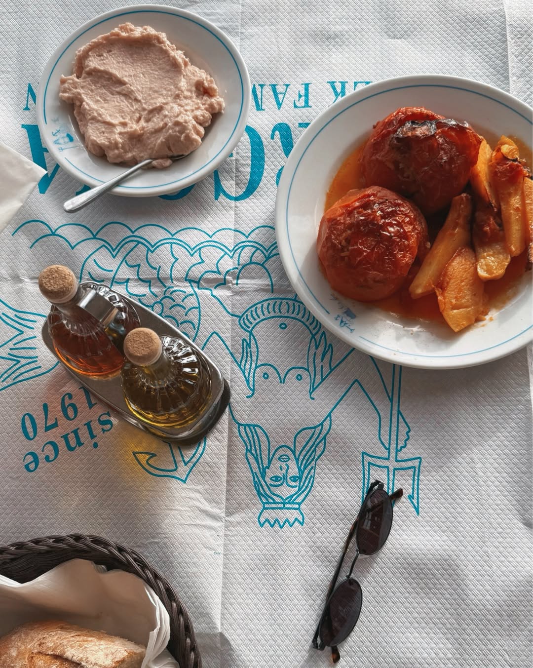 Traditional Greek taramasalata (fish roe dip) in light pink color, served with silver spoon on white plate with blue rim at Gorgona Taverna with traditional table setting